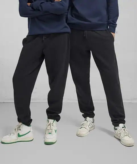 Comfy black joggers with elasticated cuffs, perfect for casual workwear or leisure, styled with sneakers and hoodies. Custom embroidery options available for work uniforms.