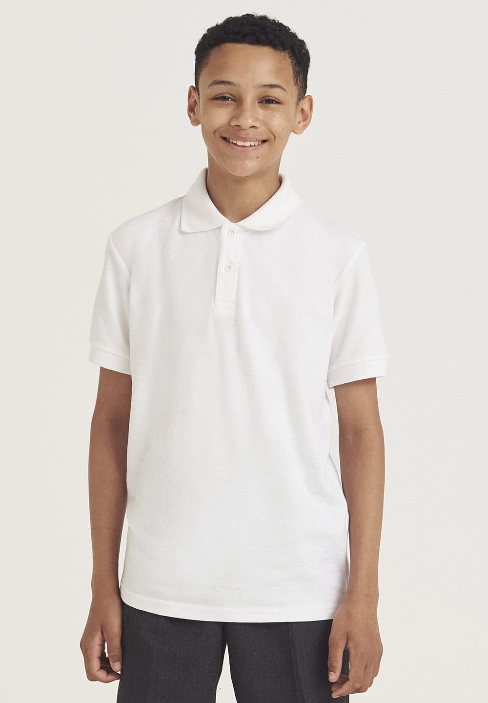Bright young boy wearing classic white embroidered workwear polo shirt for personalised uniform and work clothing, ideal for school or professional settings.