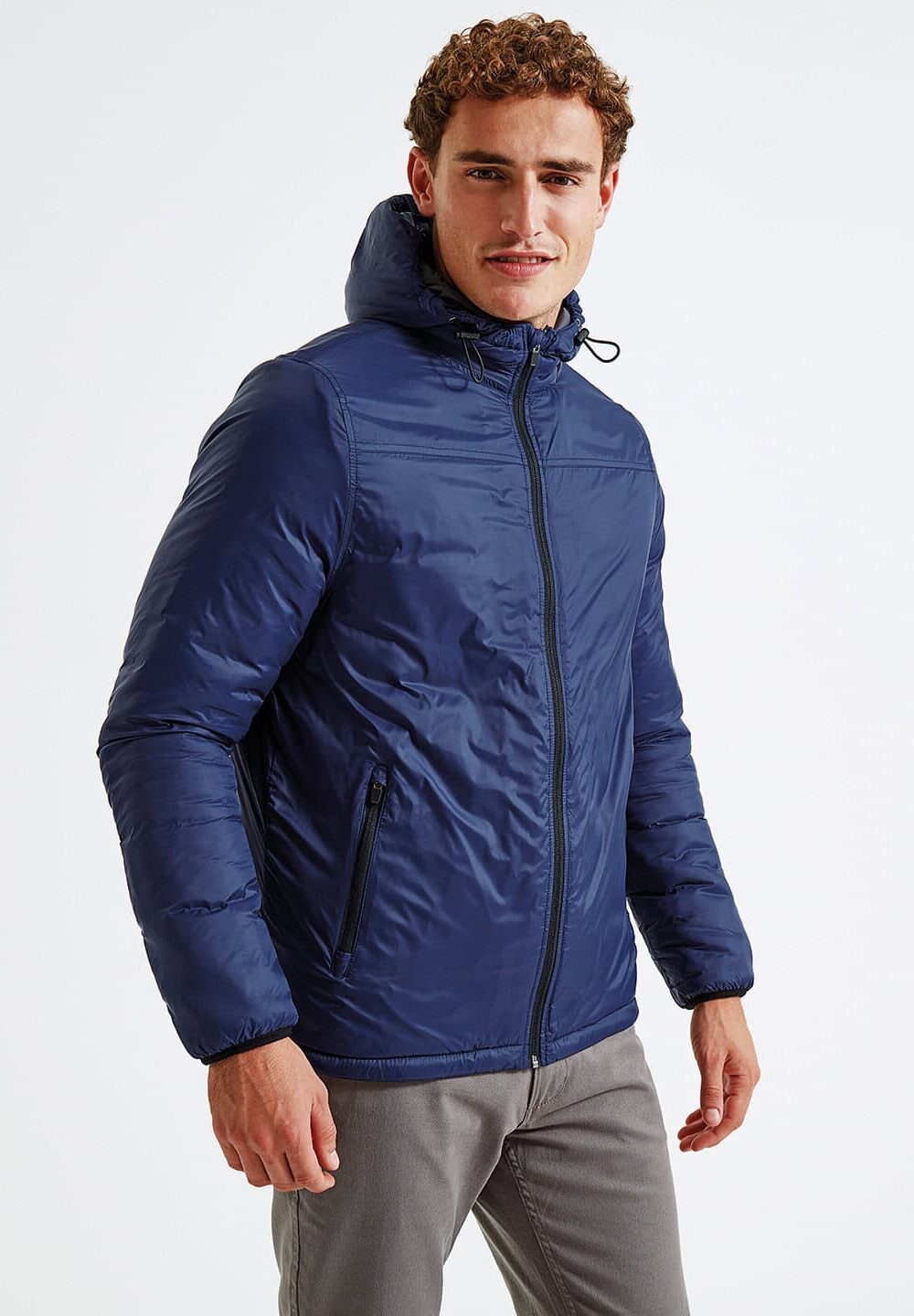 Warm navy blue puffer jacket with hood, front zipper, and side zip pockets, ideal for embroidered workwear and personalised uniforms, suitable for various outdoor work environments.