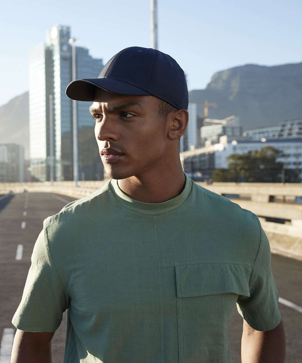 High-quality navy embroidered cap worn by a male model in an urban outdoor setting. Perfect for workwear and personalised uniforms in various industries, showcasing stylish embroidered workwear options.
