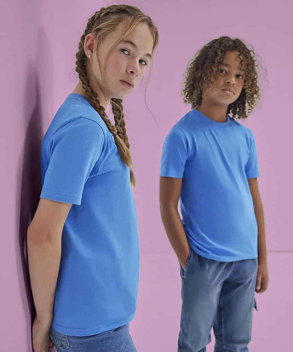 Two children wearing blue embroidered T-shirts against a pink background.