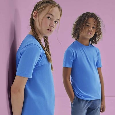 Two children wearing blue embroidered T-shirts against a pink background.