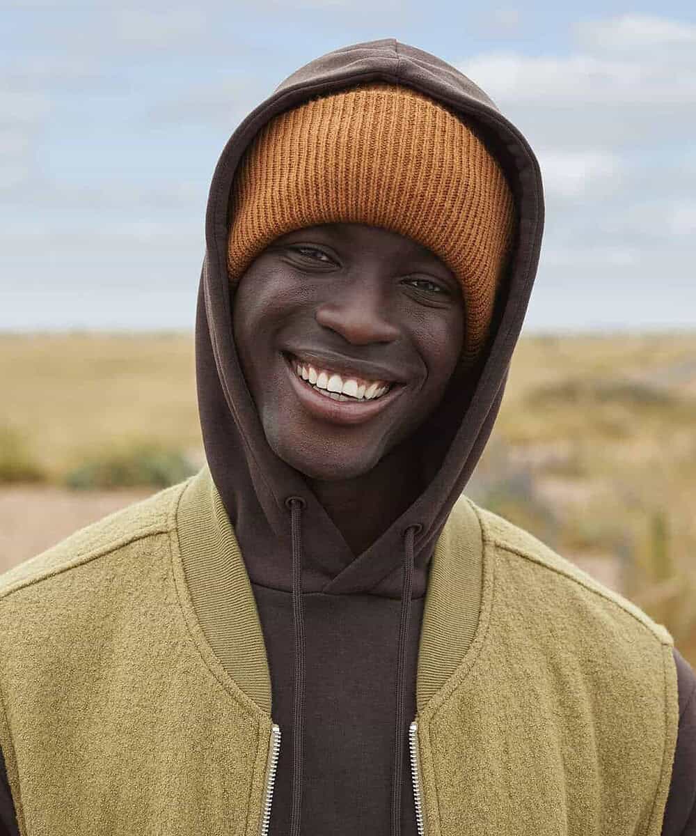 Man wearing Beechfield B385R deep-cuffed beanie outdoors, smiling.