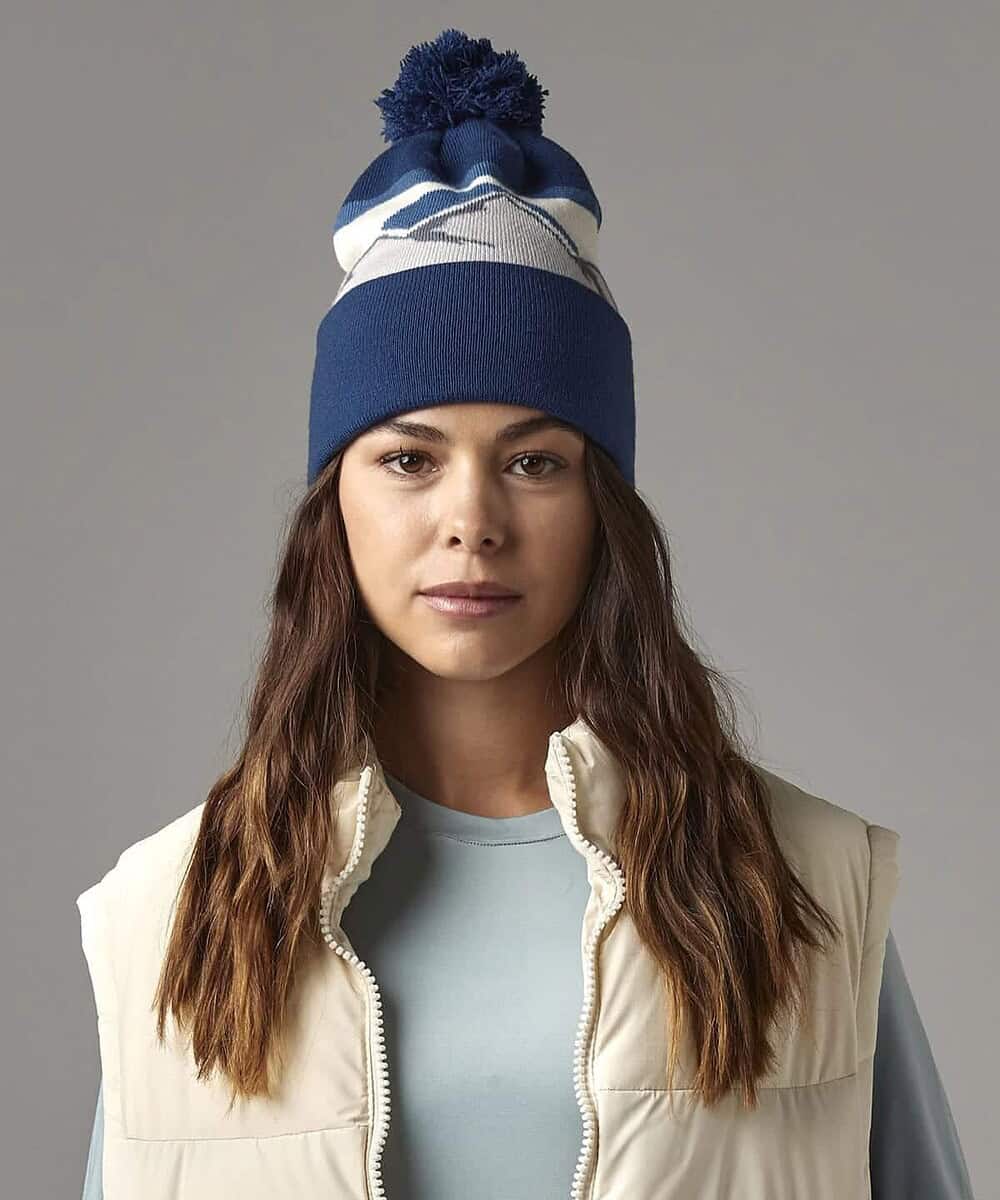 Embroidered Mountain Peaks Pom Pom Beanie in blue with white accents, perfect for custom branding an.
