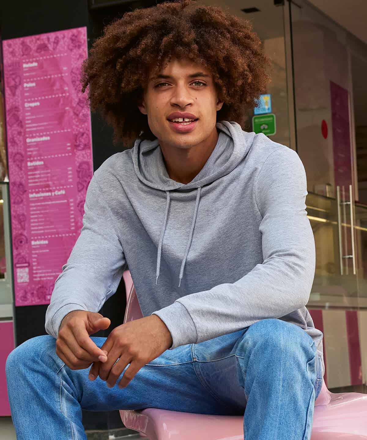 Bright young man wearing custom embroidered casual hoodie at shop entrance.