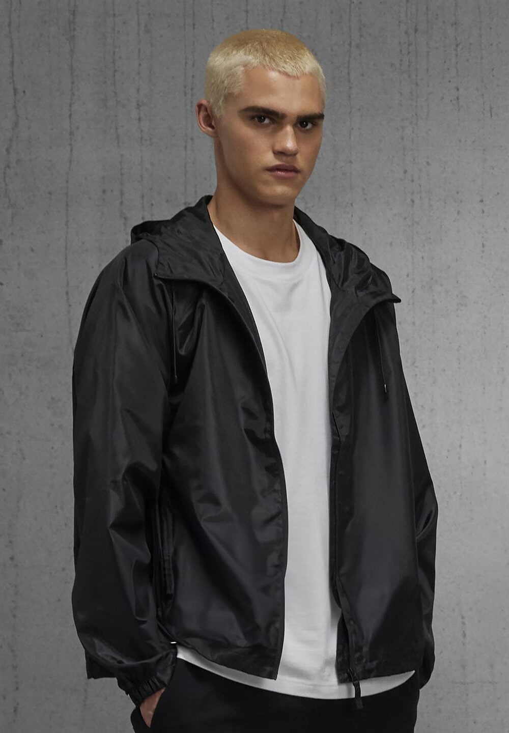 Light-skinned man wearing black waterproof windbreaker jacket for work or sports.