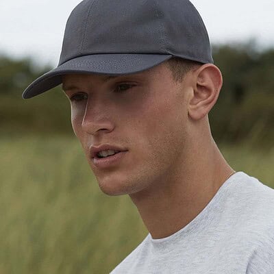 Man wearing a grey organic cotton 6-panel cap outdoors.