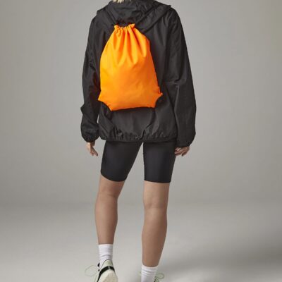 Bright orange Bagbase BG010 gymsac backpack on model's back.