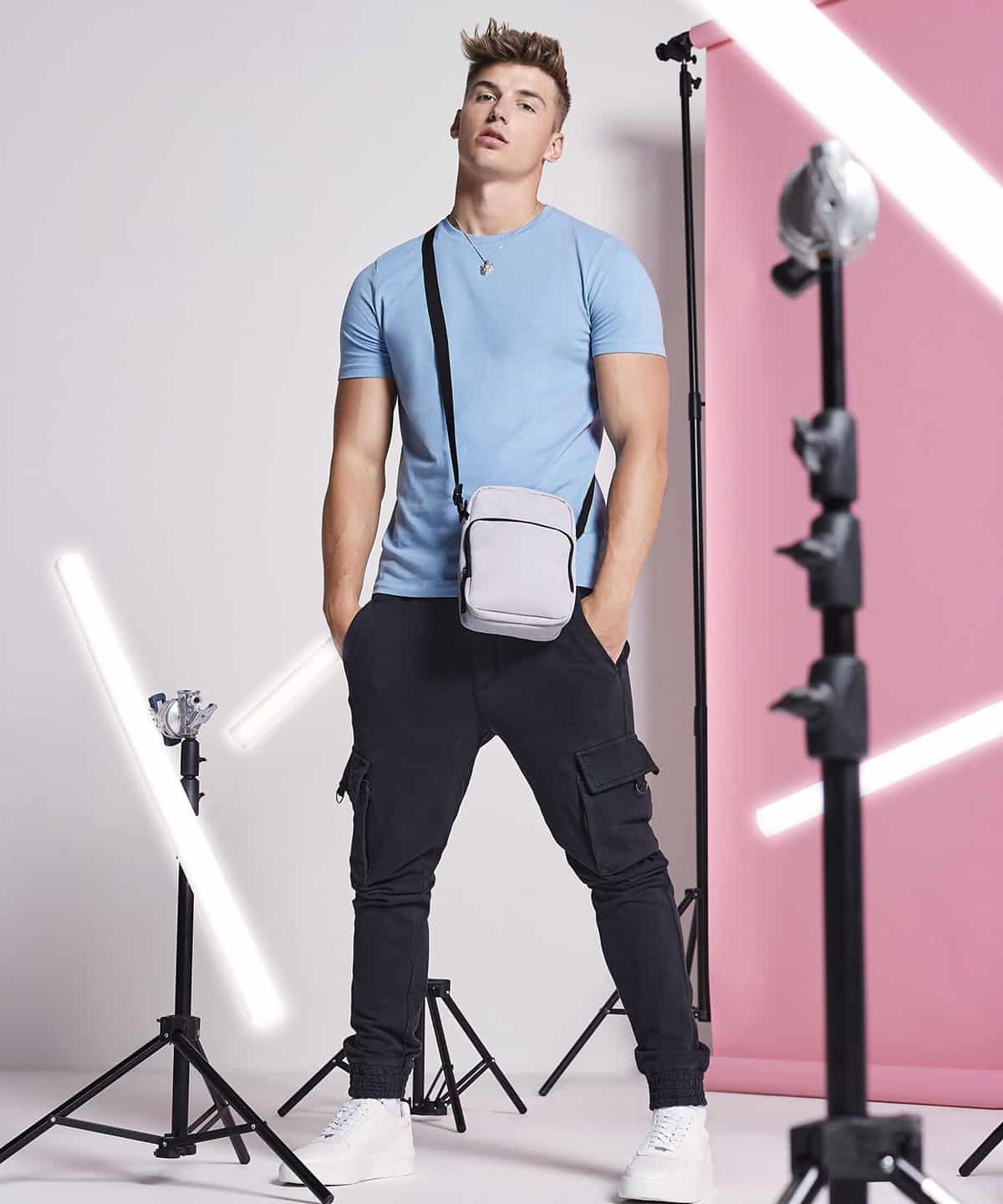 Bright young male model wearing casual T-shirt and cargo joggers with embroidered workwear and personalised uniforms, demonstrating custom embroidery for workwear branding and promotional clothing, studio photoshoot.