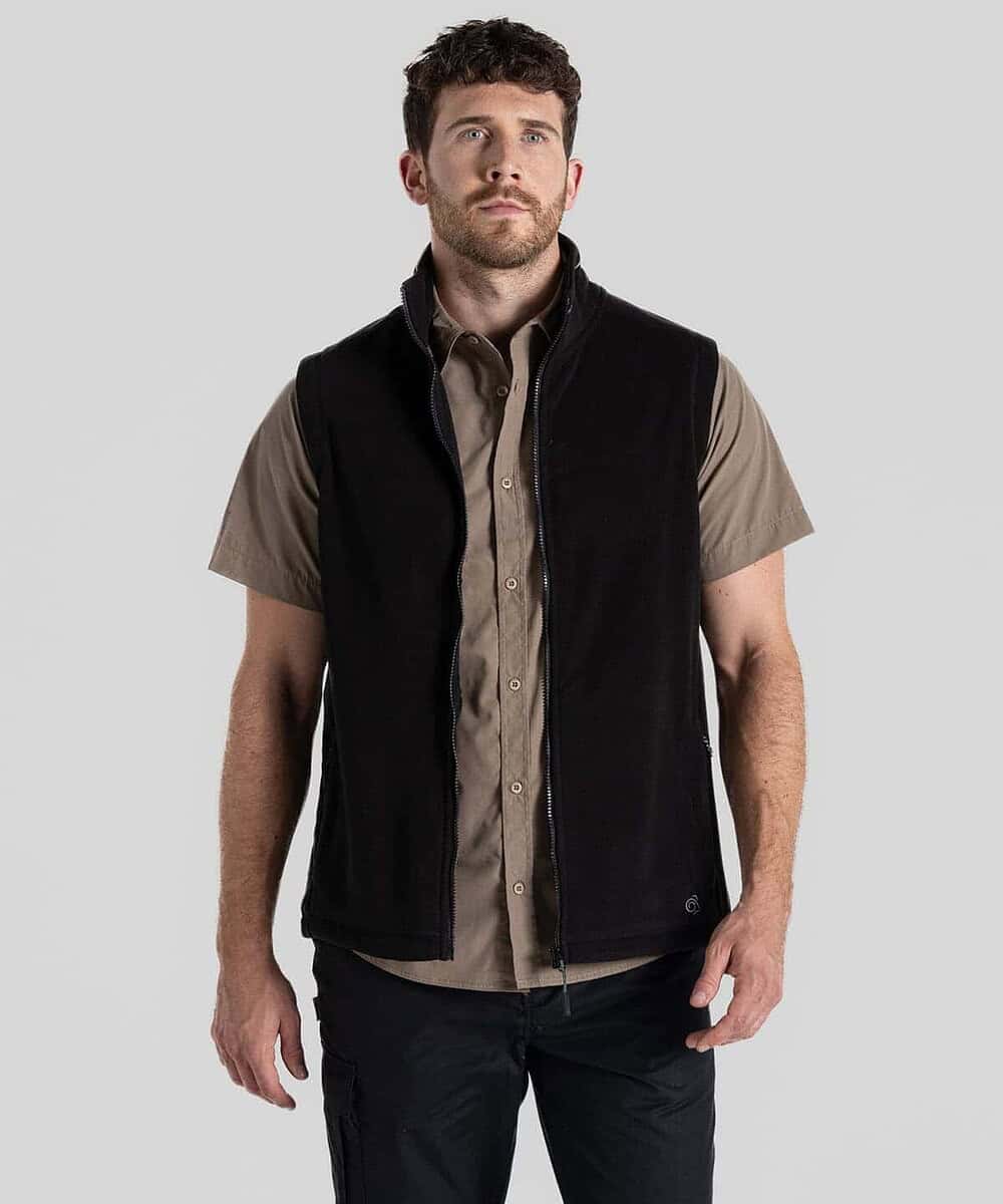 Man wearing black fleece vest over beige shirt, casual outdoor look.