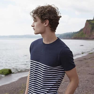 Man wearing a navy and white striped Breton T-shirt on the beach.