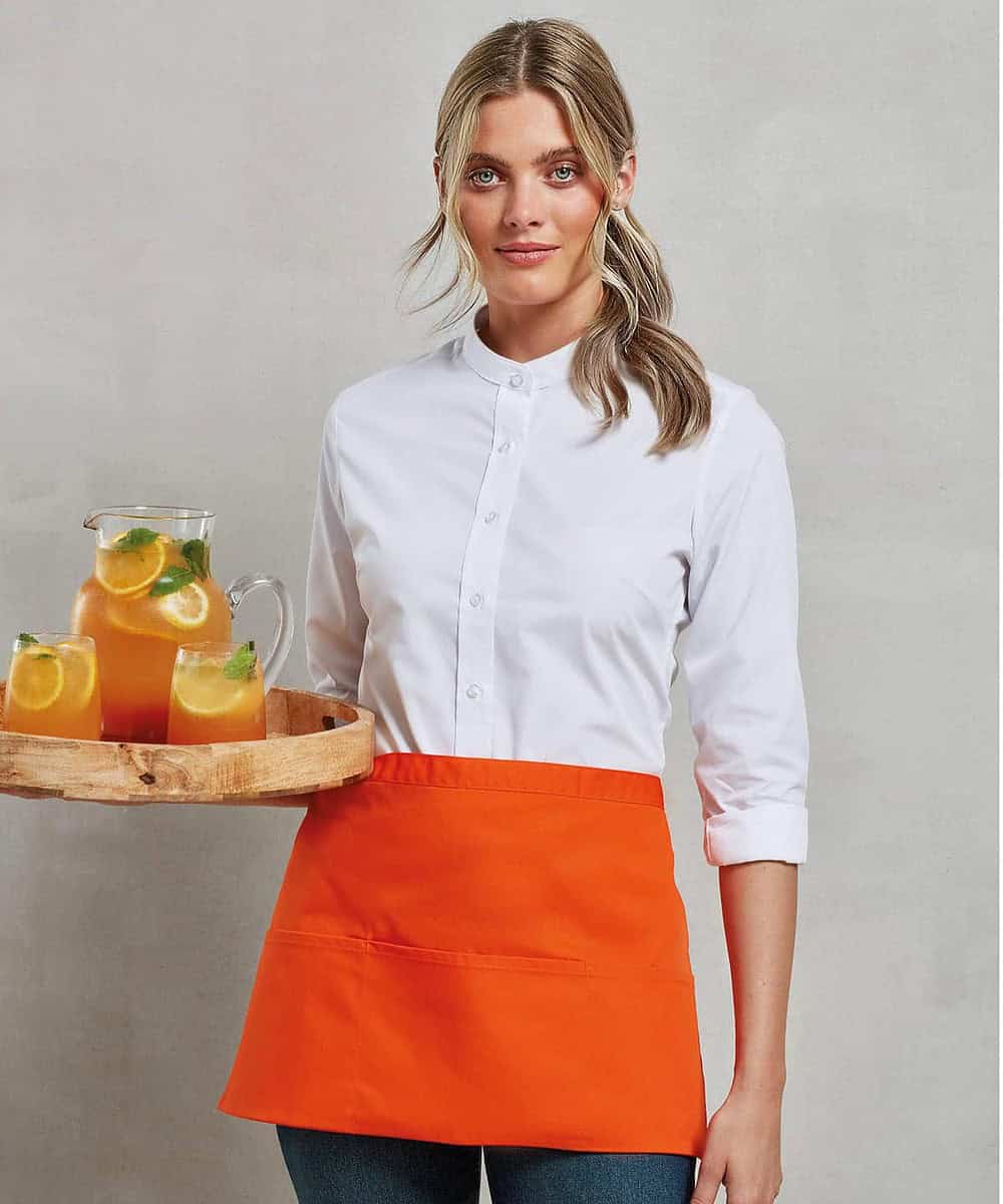 Woman wearing a bright orange 3-pocket apron with a white shirt, holding a tray of drinks.