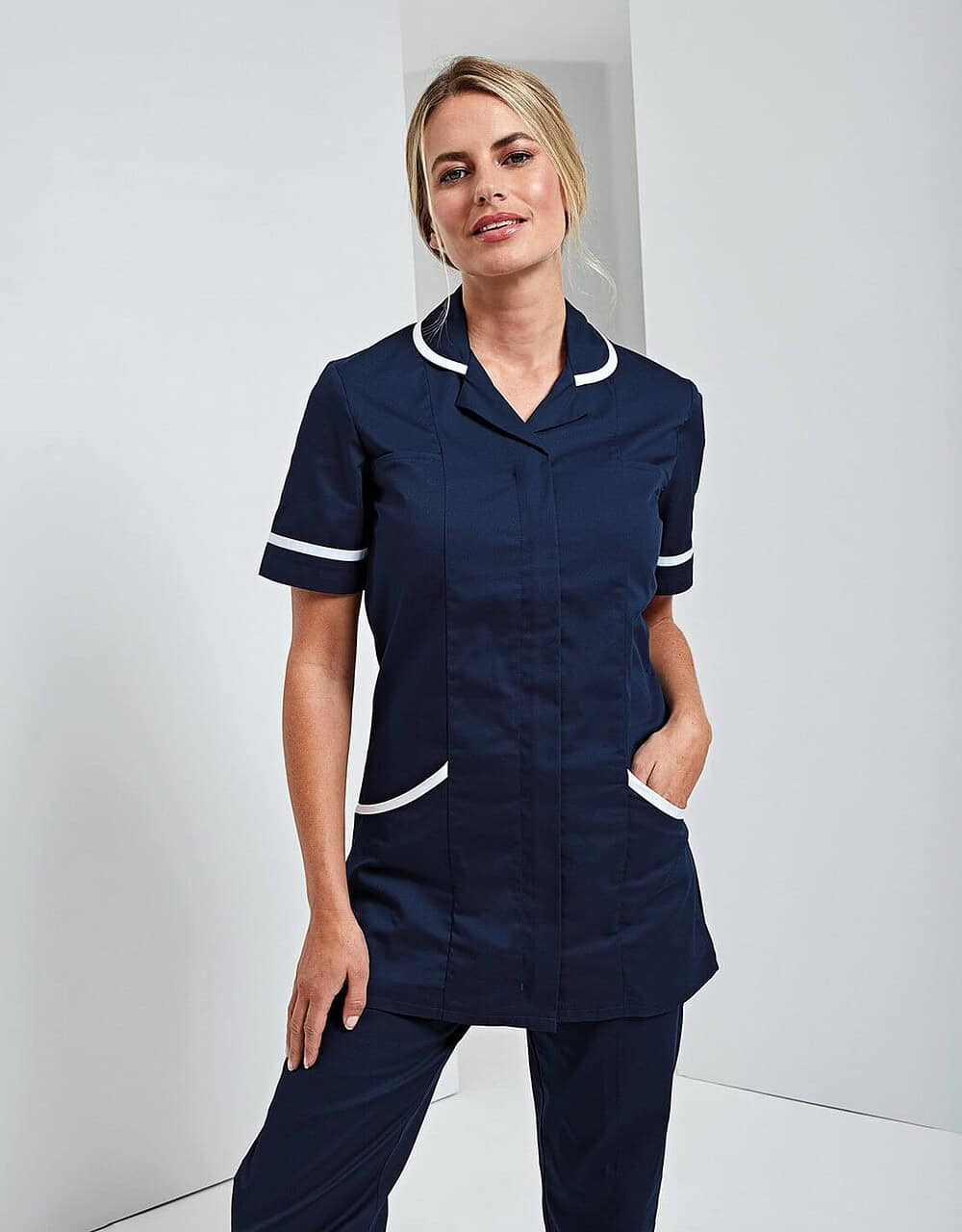 Elegant navy blue nurse uniform with white piping, short sleeves, and multiple pockets, designed for professional healthcare staff. Perfectly embroidered workwear for hospitals and clinics.