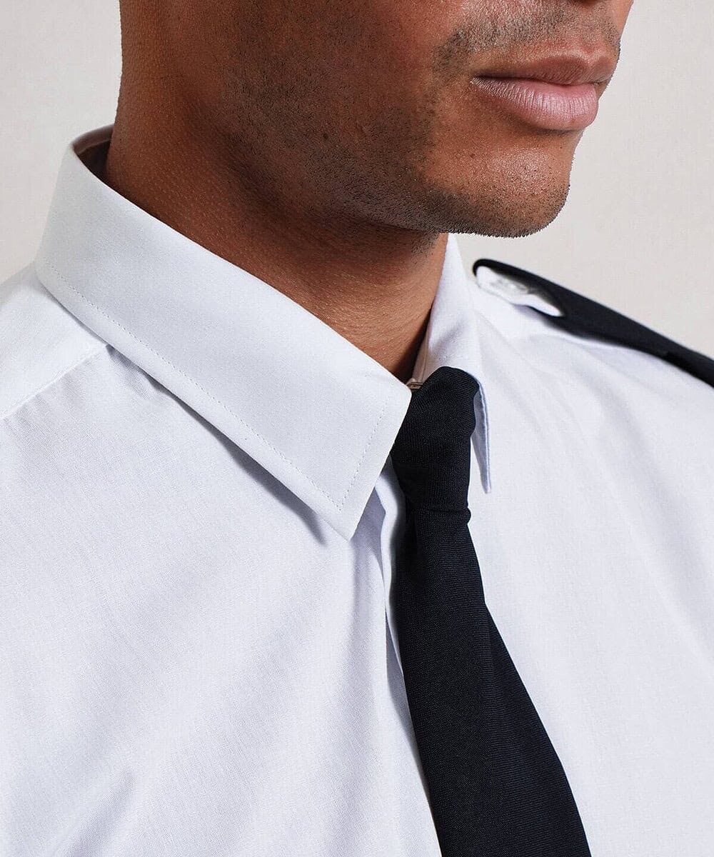 Close-up of a person wearing a white shirt with black epaulettes and a black tie.