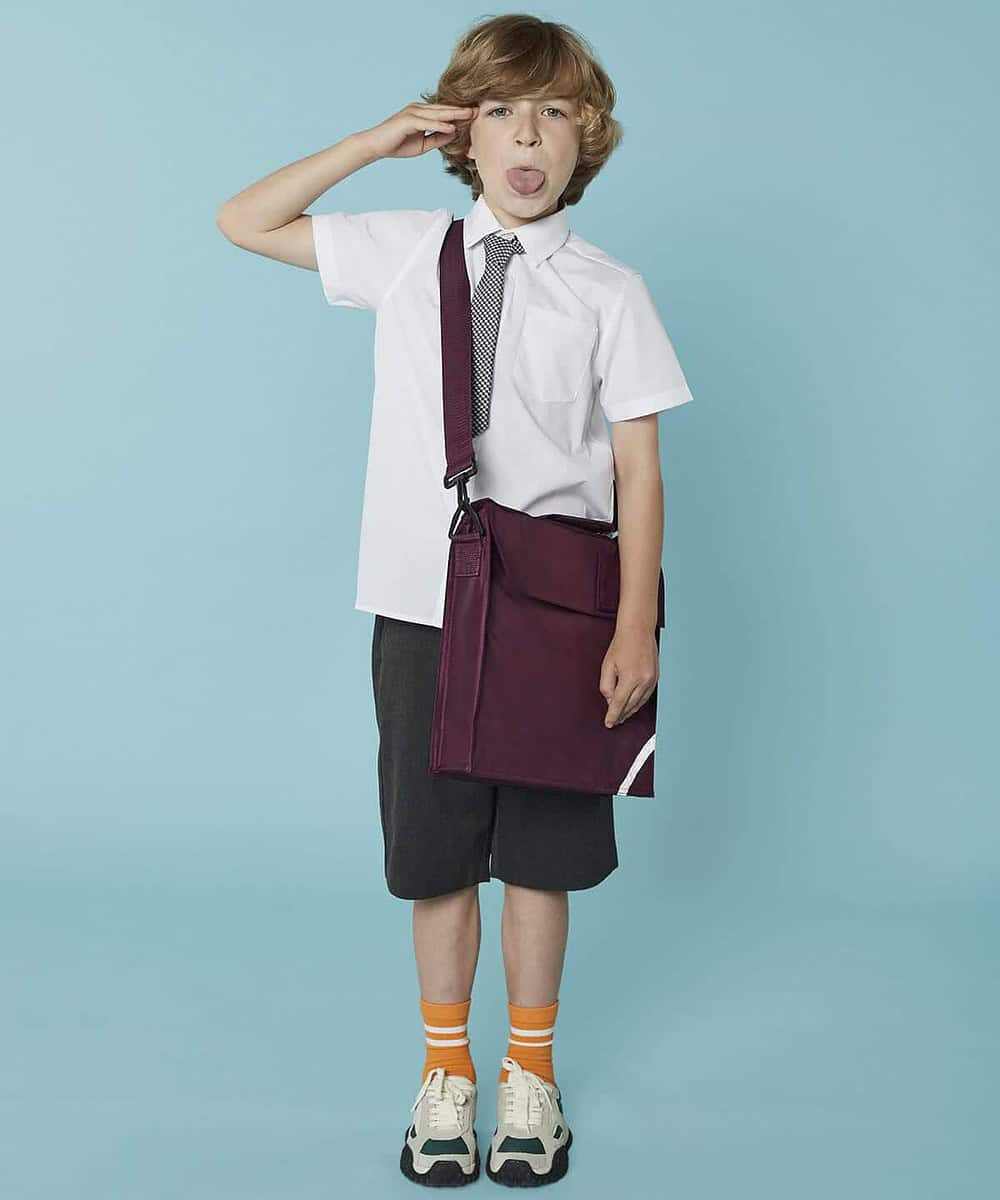 Child in school uniform with personalised maroon book bag and playful expression.