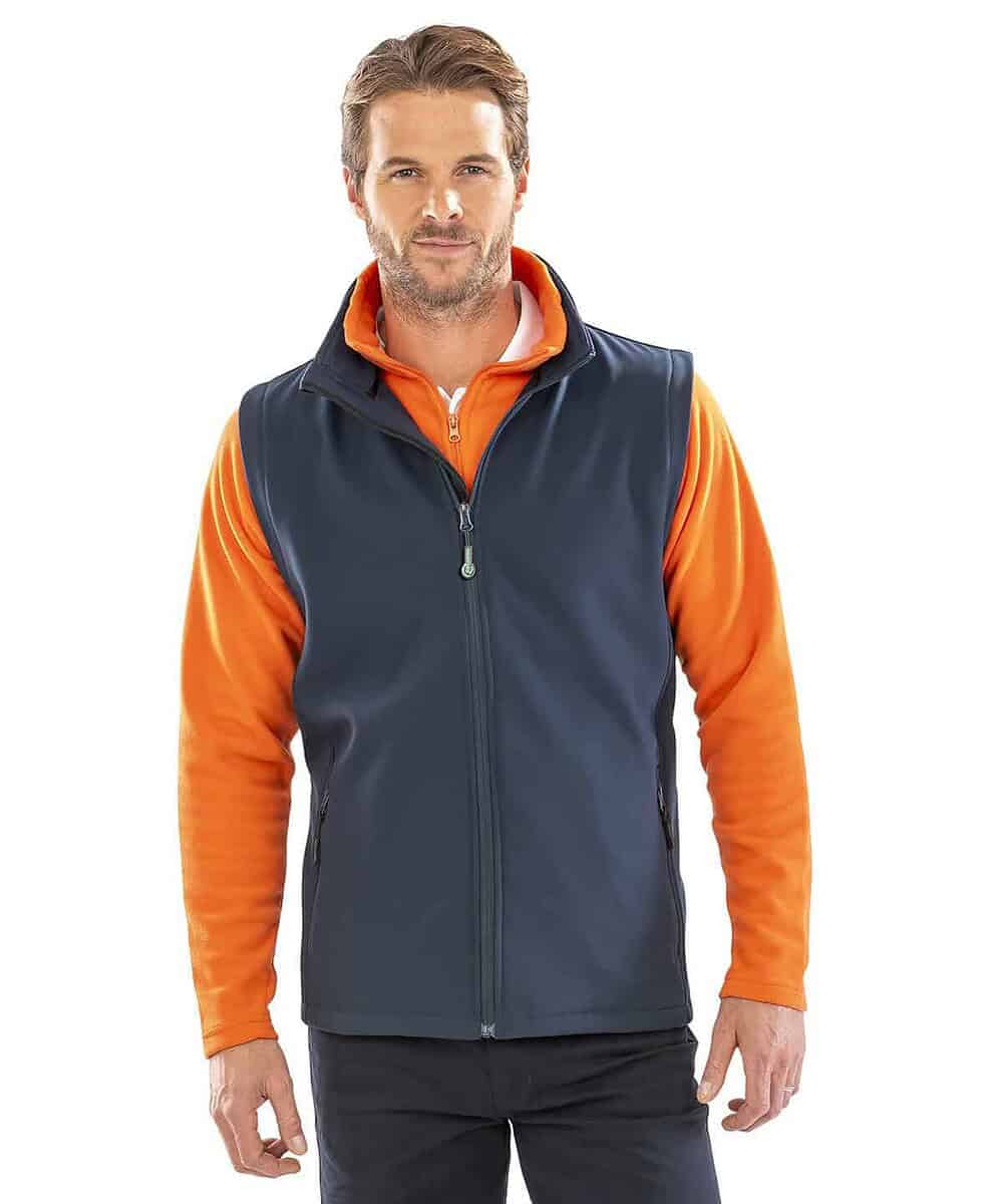 An image of a man wearing a navy blue and orange printable softshell bodywarmer, ideal for personali.
