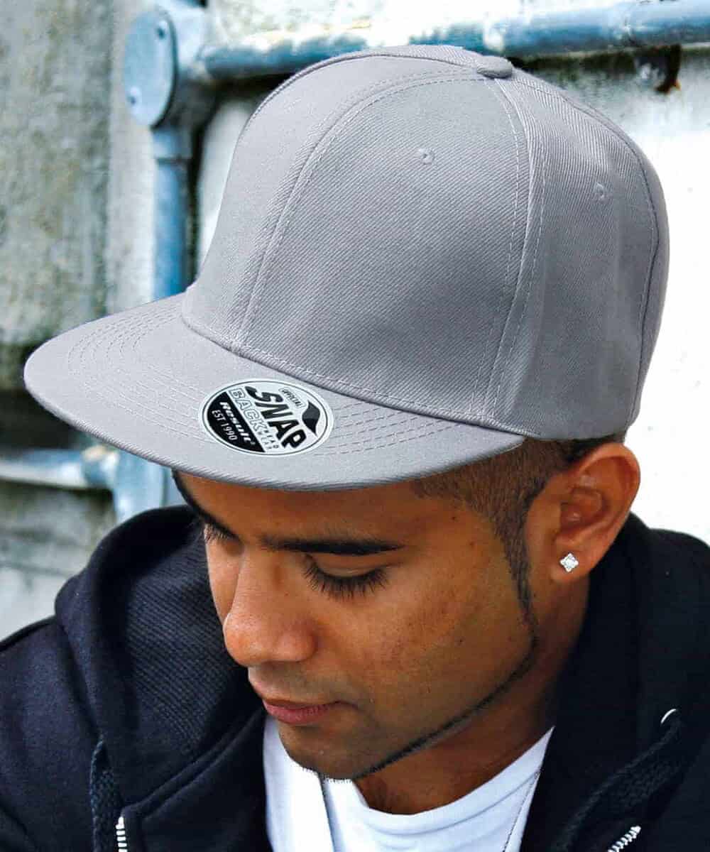 Grey Bronx flat peak snapback cap with logo, worn by a young man.