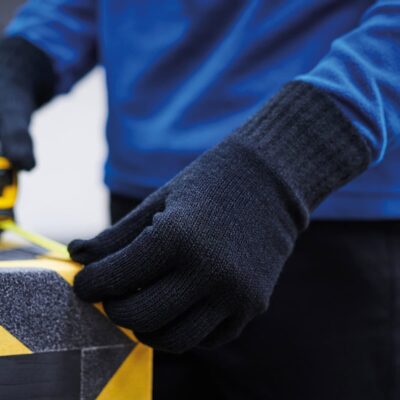 Close-up of men's black work gloves with textured grip, worn during manual task.