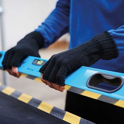Close-up of person wearing black fingerless gloves holding a spirit level.