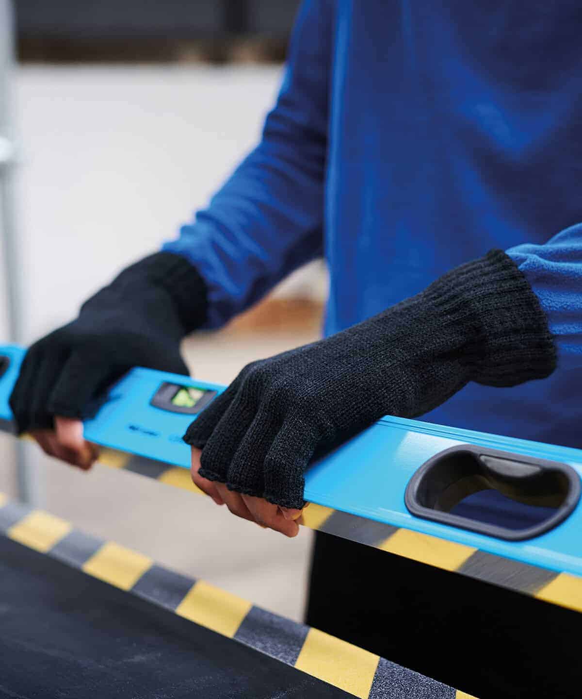 Close-up of person wearing black fingerless gloves holding a spirit level.