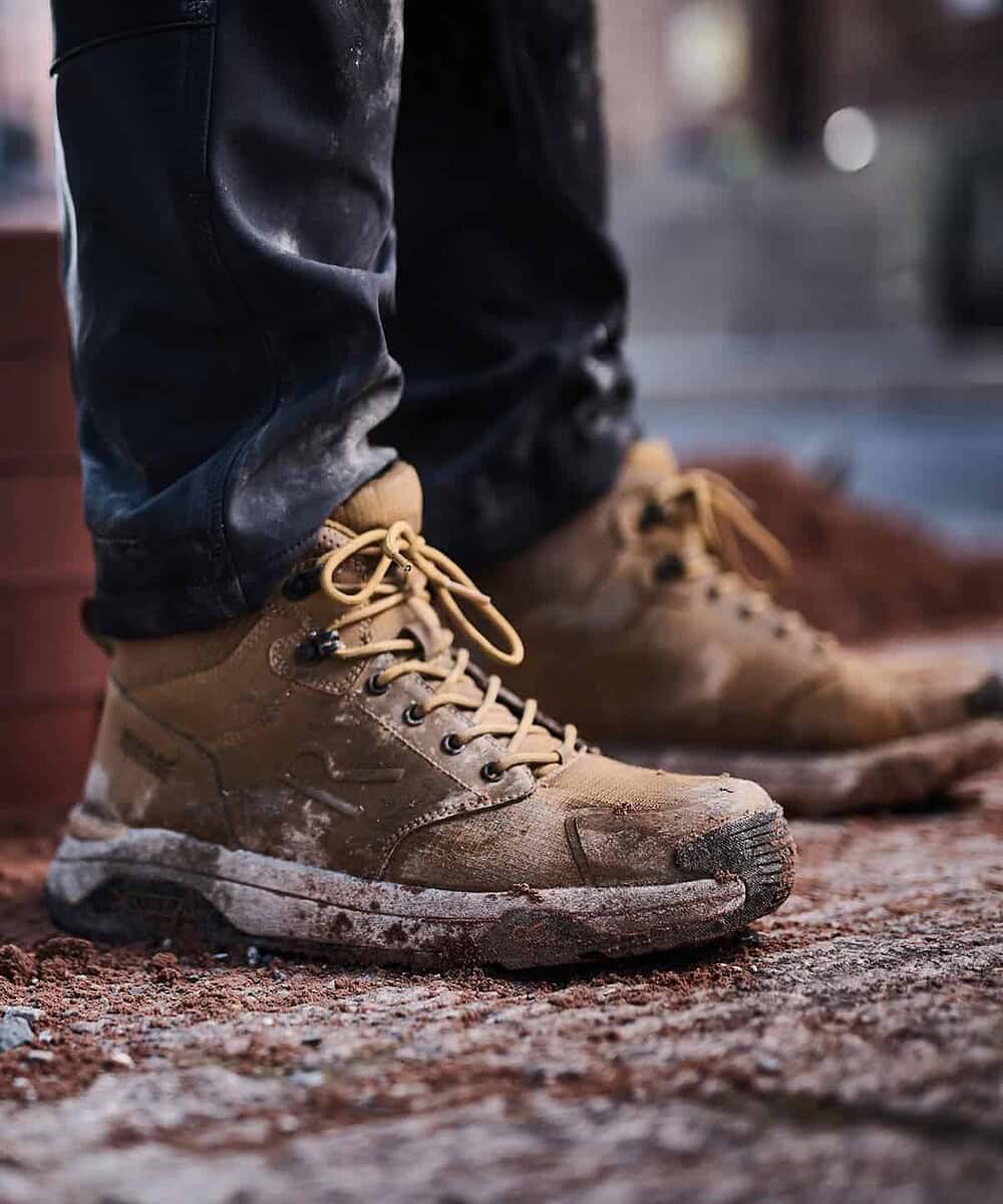 Durable safety work boots with muddy soles, suitable for rugged environments.