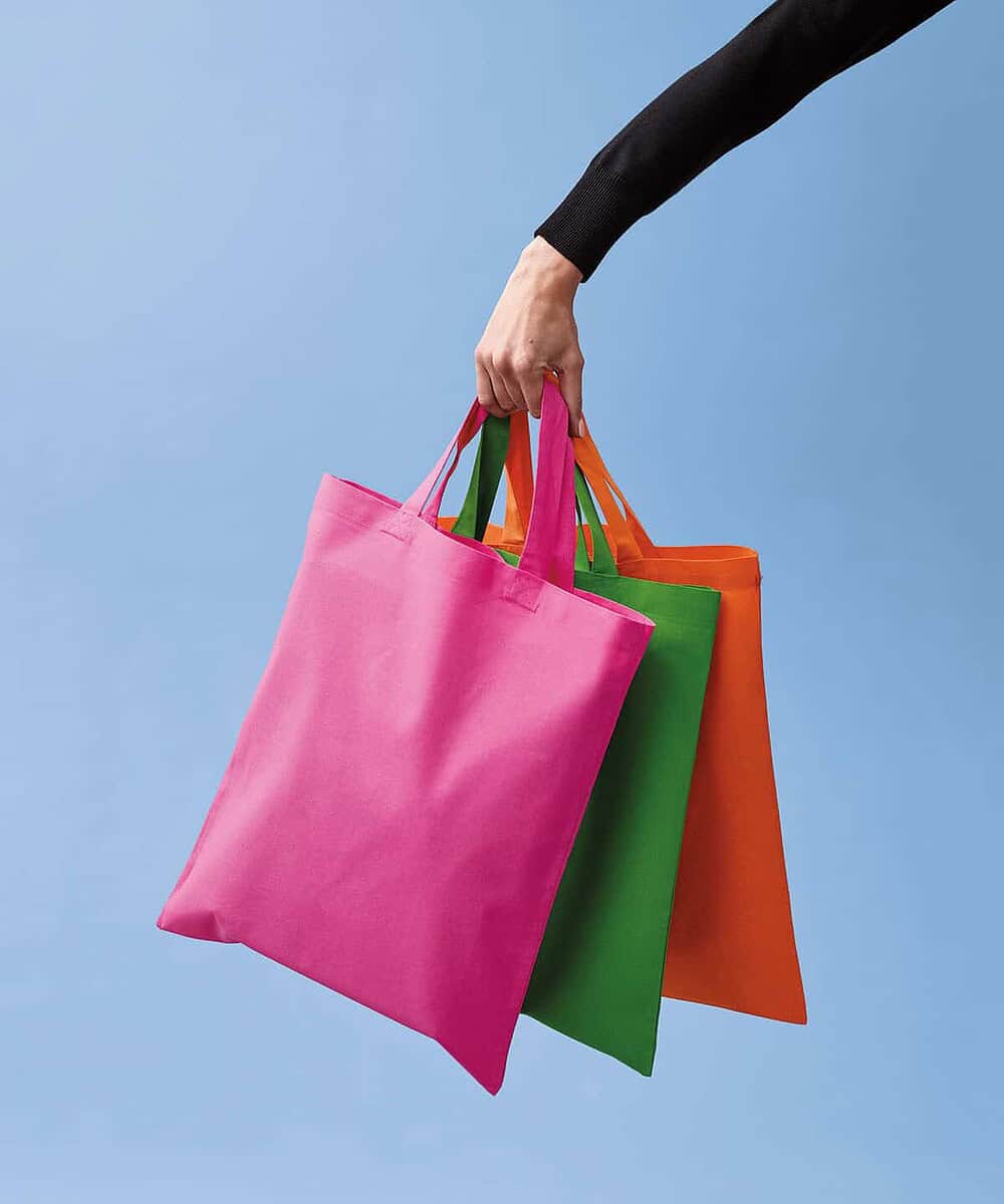 Cotton shopper bags in pink, green, and orange with short handles for workwear or promotional use.