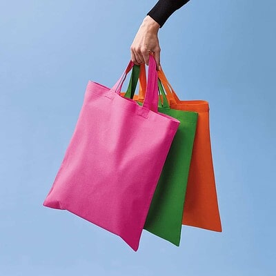 Cotton shopper bags in pink, green, and orange with short handles for workwear or promotional use.