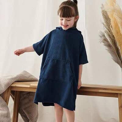 Child wearing navy Towel City TC811 kids poncho with logo, casual indoor wear.