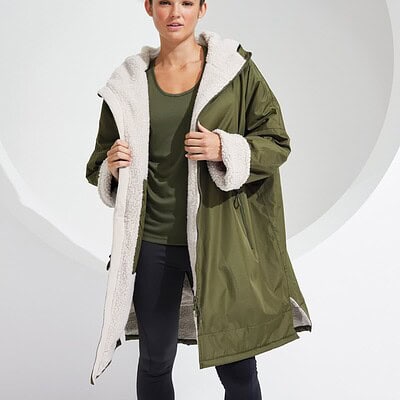 Woman wearing a green waterproof changing robe with fleece lining, suitable for outdoor activities.