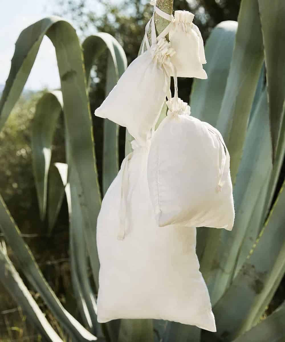 Organic cotton drawstring bags hanging outdoors, ideal for custom branding and eco-friendly promotio.