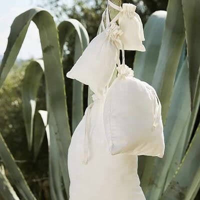 Organic cotton drawstring bags hanging outdoors, ideal for custom branding and eco-friendly promotio.