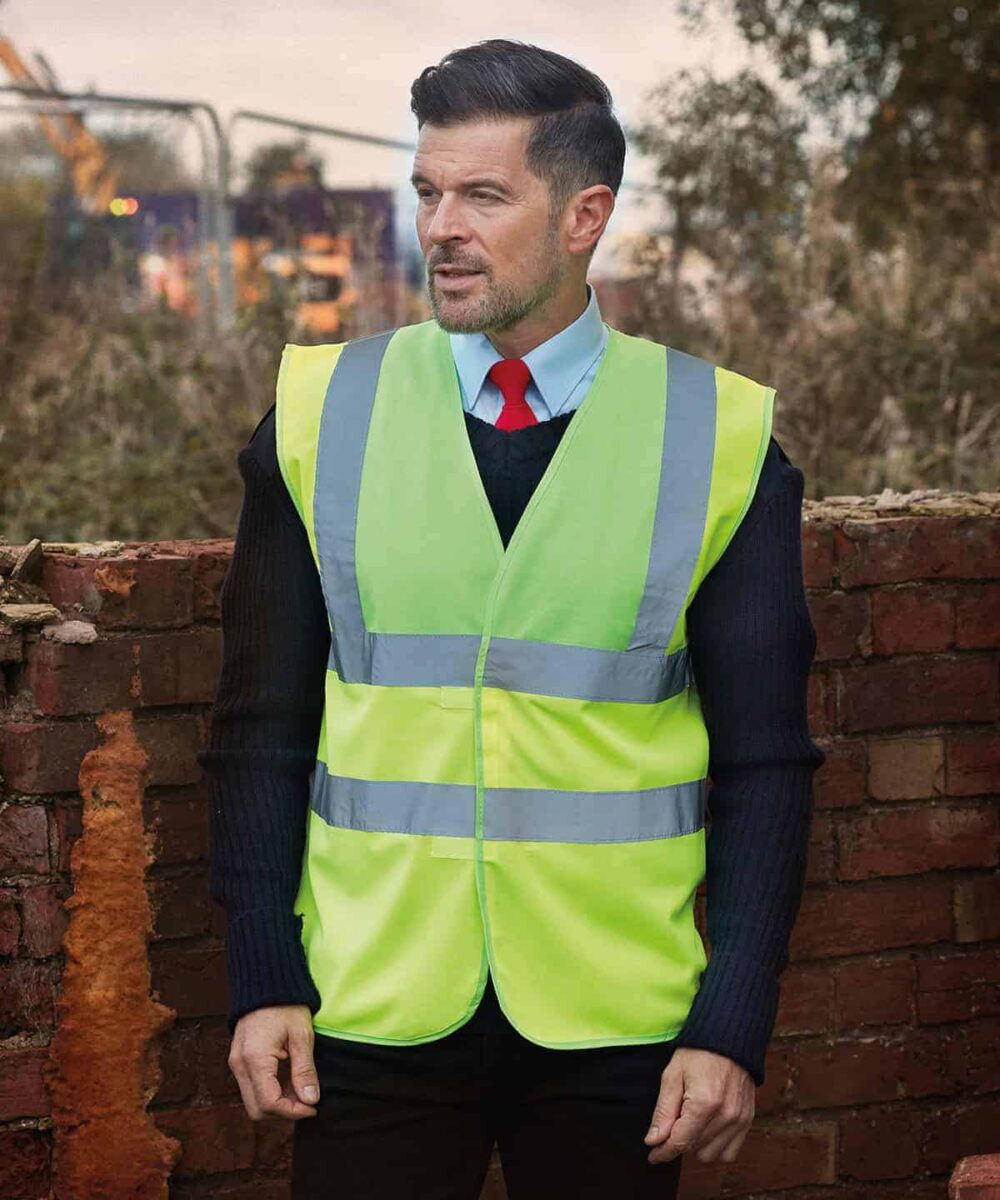 Man wearing high-visibility yellow waistcoat with reflective strips outdoors.