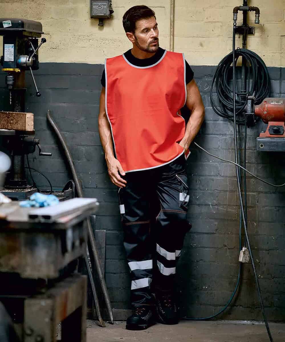 Man wearing Yoko YK009 Hi-Vis Reflective Border Tabard in workshop setting.