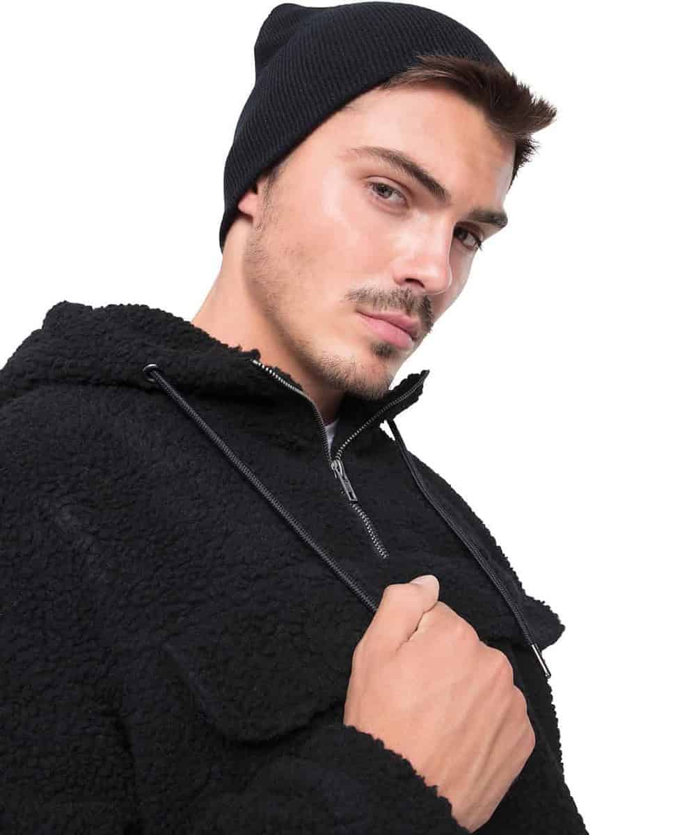 Man wearing a black Flexfit Yupoong heavyweight beanie, showcasing branded headwear.