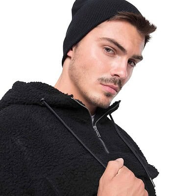 Man wearing a black Flexfit Yupoong heavyweight beanie, showcasing branded headwear.