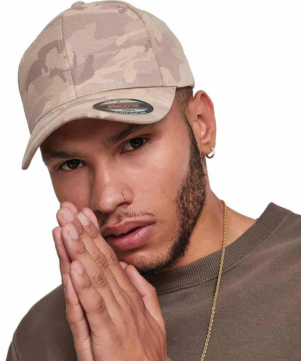 Man wearing a beige camouflage Flexfit cap with logo detail.