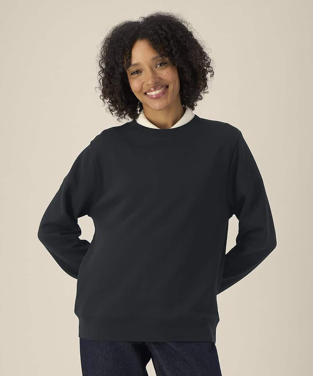 Woman wearing a black Stanley/Stella Stella Thinker sweatshirt, casual and comfortable.